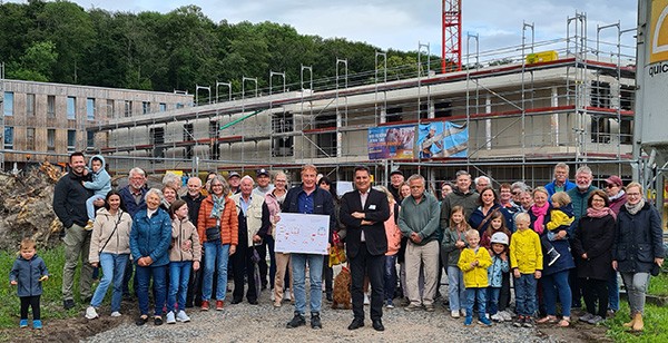 Vor einer großen mehrstöckigen Baustelle stehen rund 50 Personen